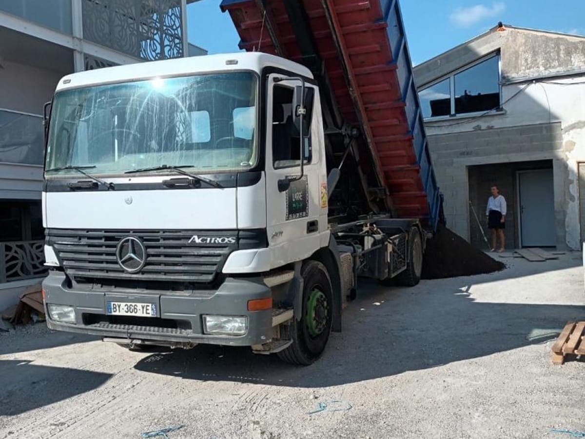 Camion porte-benne basculant une benne pour vider les terres d'un chantier